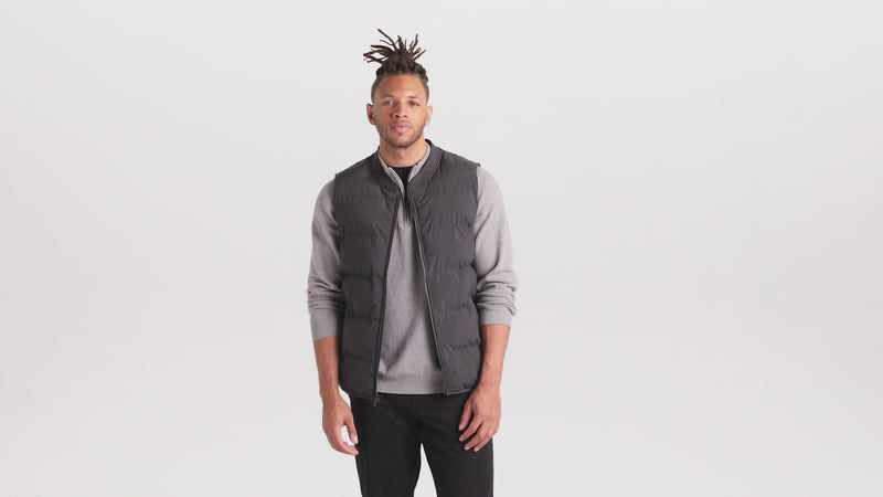 video of male model in a grey puffer vest, grey sweater and black jeans